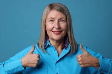 Senior woman showing thumbs up on blue background