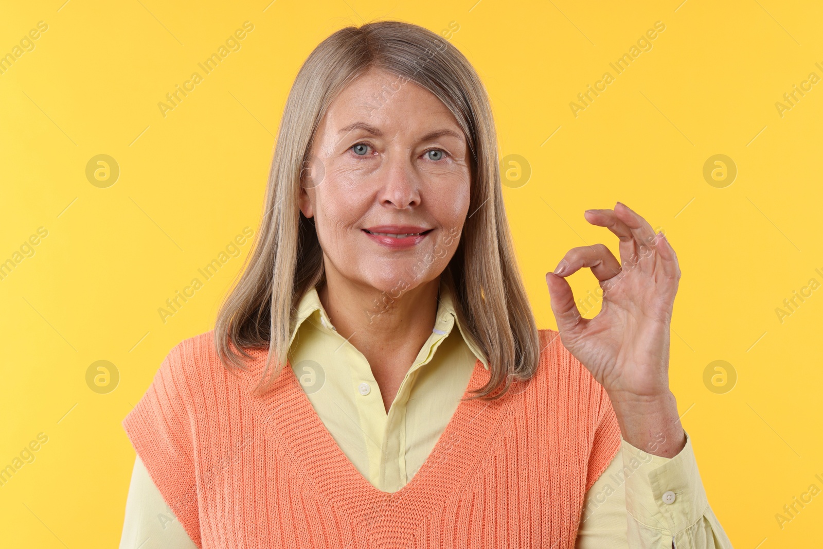 Photo of Senior woman showing okay gesture on yellow background