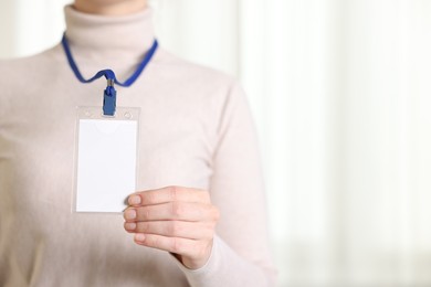 Photo of Woman with blank badge indoors, closeup. Space for text