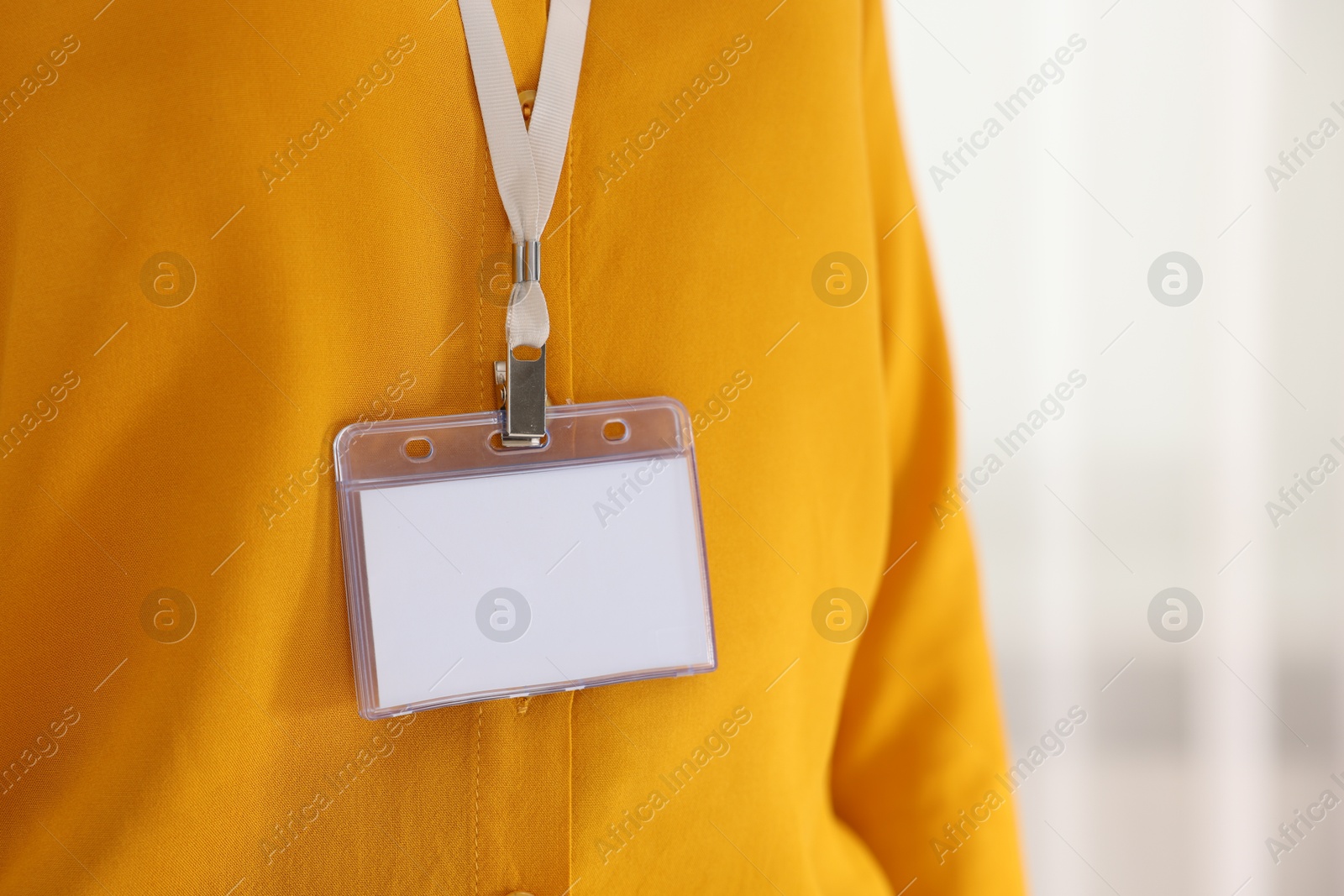 Photo of Woman with blank badge indoors, closeup. Space for text