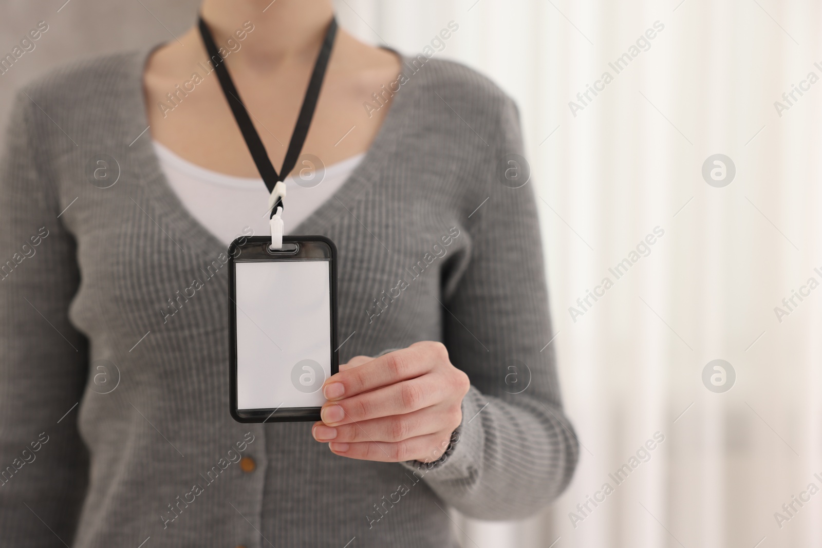 Photo of Woman with blank badge indoors, closeup. Space for text