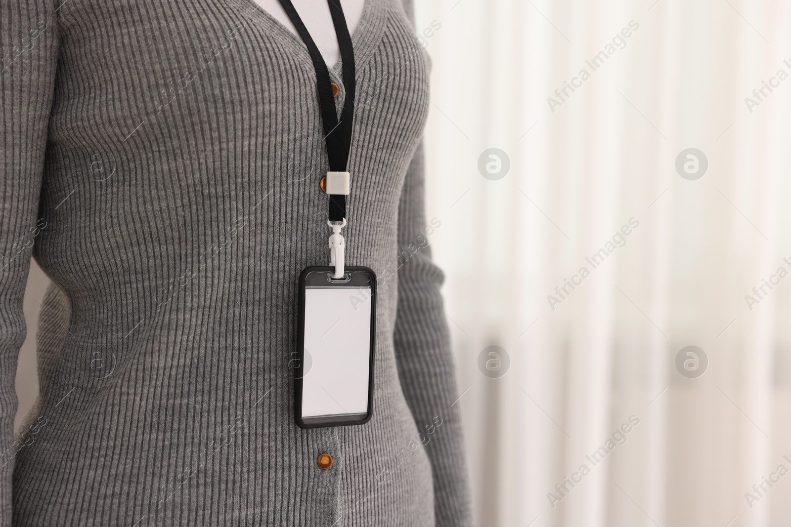 Photo of Woman with blank badge indoors, closeup. Space for text