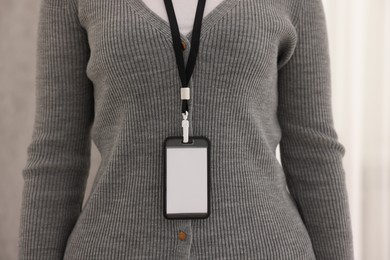 Photo of Woman with blank badge indoors, closeup view