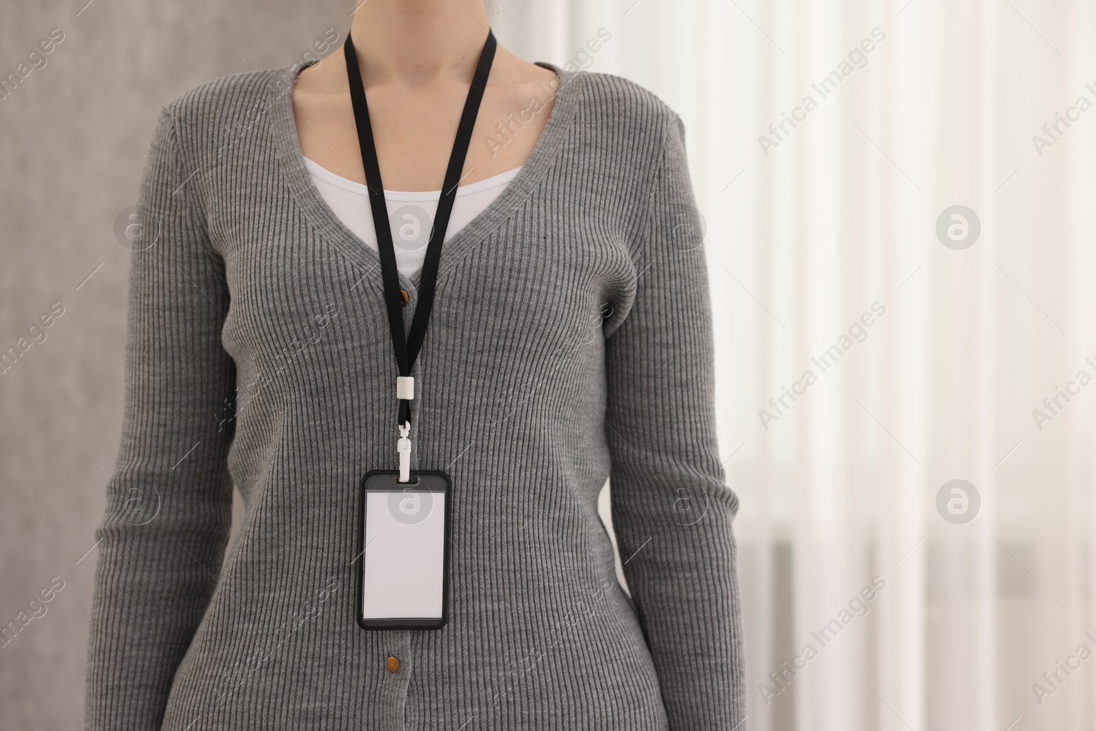 Photo of Woman with blank badge indoors, closeup. Space for text