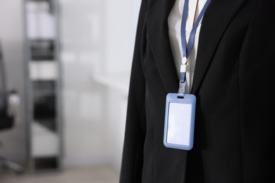 Photo of Woman with blank badge indoors, closeup. Space for text