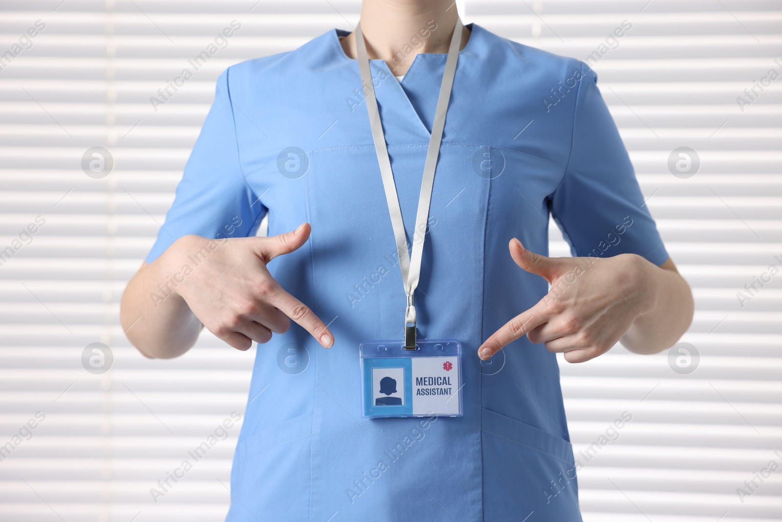 Photo of Medical assistant pointing at her badge in clinic, closeup