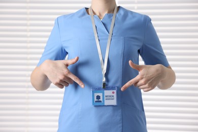 Photo of Medical assistant pointing at her badge in clinic, closeup