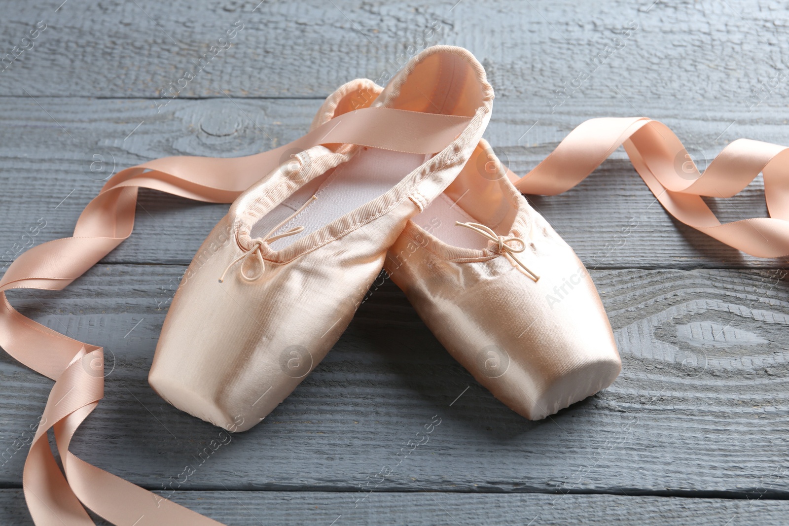 Photo of Pair of beautiful pointe shoes on grey wooden table