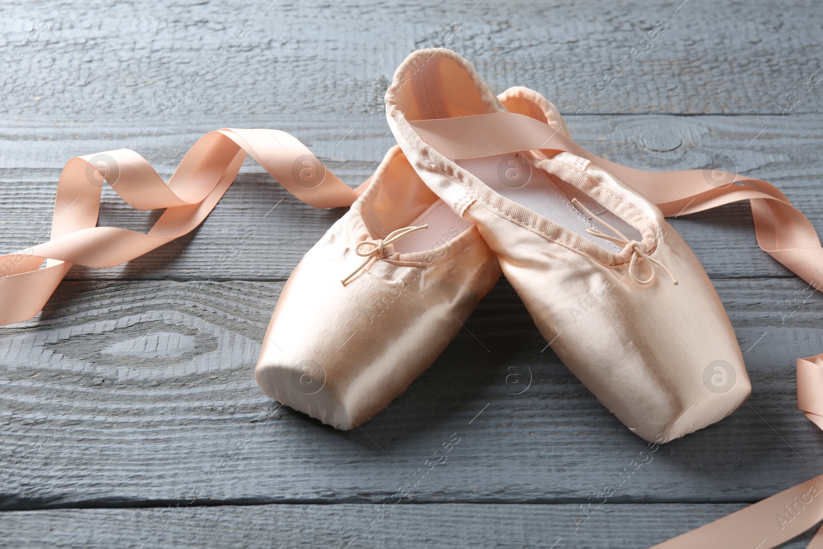 Photo of Pair of beautiful pointe shoes on grey wooden table