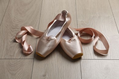 Photo of Pair of beautiful pointe shoes on wooden floor