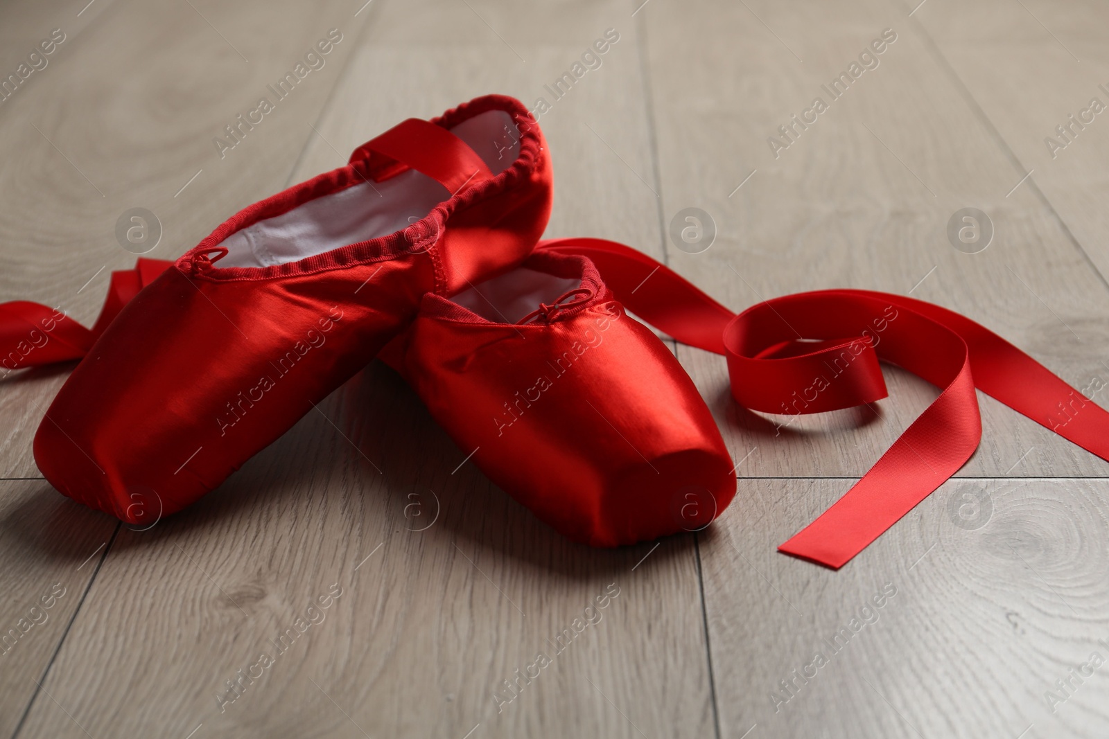 Photo of Pair of red pointe shoes on wooden floor