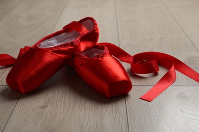 Photo of Pair of red pointe shoes on wooden floor