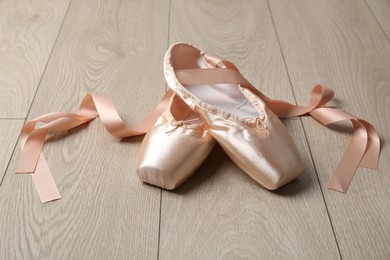 Photo of Pair of beautiful pointe shoes on wooden floor