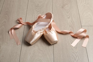 Photo of Pair of beautiful pointe shoes on wooden floor