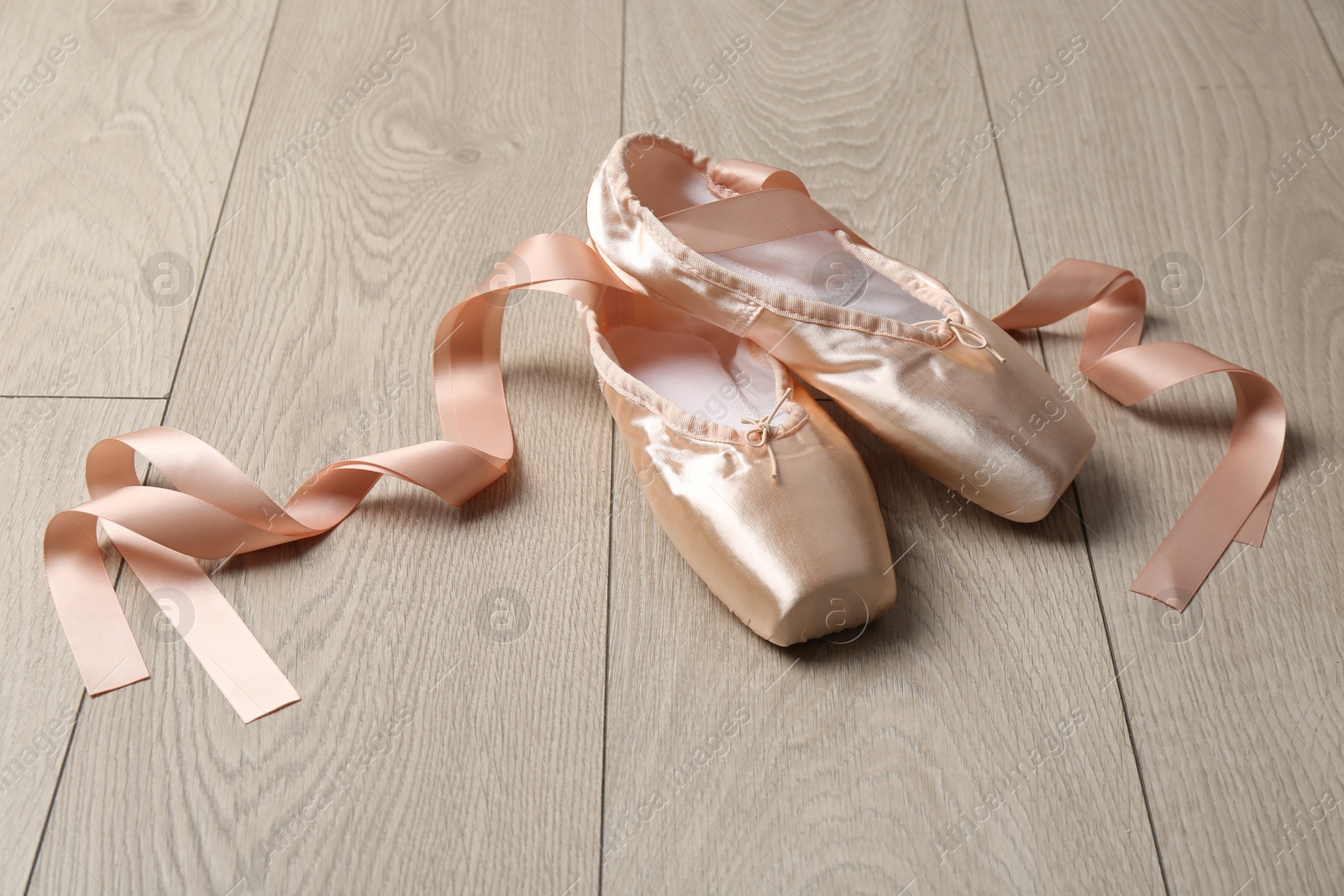 Photo of Pair of beautiful pointe shoes on wooden floor