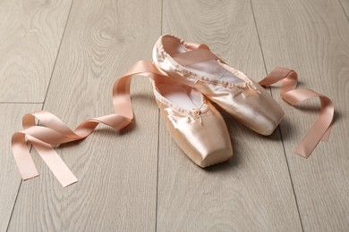 Photo of Pair of beautiful pointe shoes on wooden floor