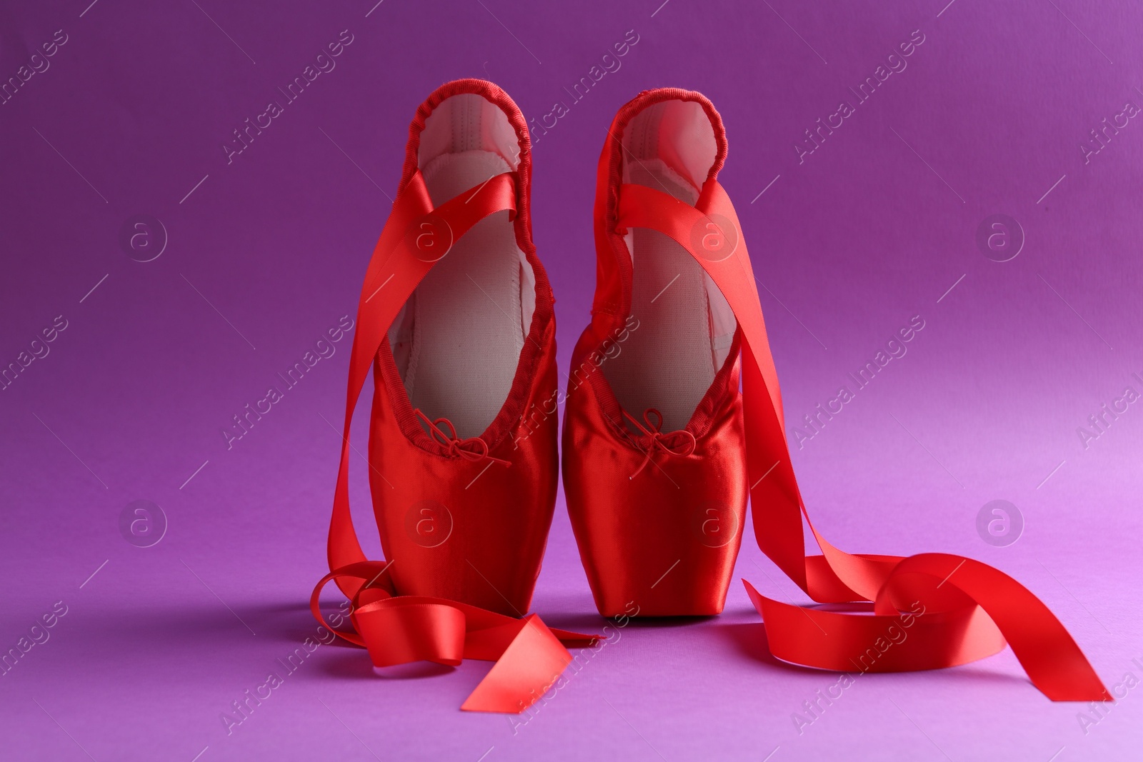 Photo of Pair of red pointe shoes on purple background