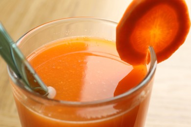 Photo of Fresh carrot juice in glass on light table, closeup