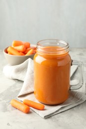 Photo of Fresh carrot juice in mason jar and vegetables on gray textured table