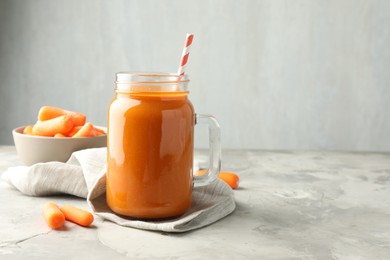 Photo of Fresh carrot juice in mason jar and vegetables on gray textured table, space for text