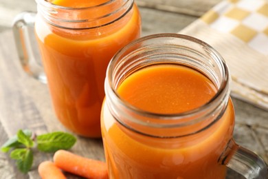 Photo of Fresh carrot juice in mason jars on table, closeup