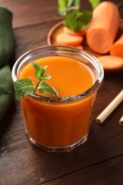 Photo of Fresh carrot juice and mint in glass on wooden table, closeup