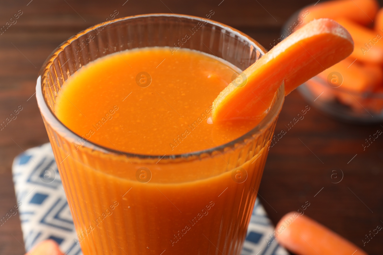 Photo of Fresh carrot juice in glass on brown table, closeup