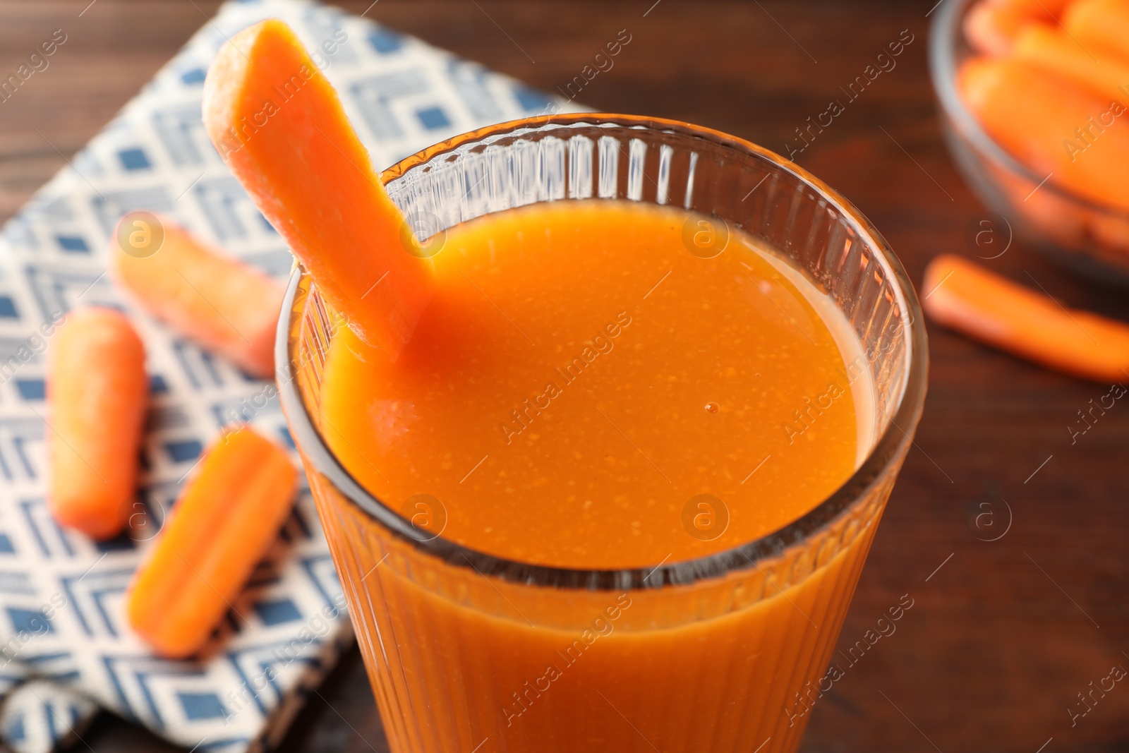 Photo of Fresh carrot juice in glass on brown table, closeup