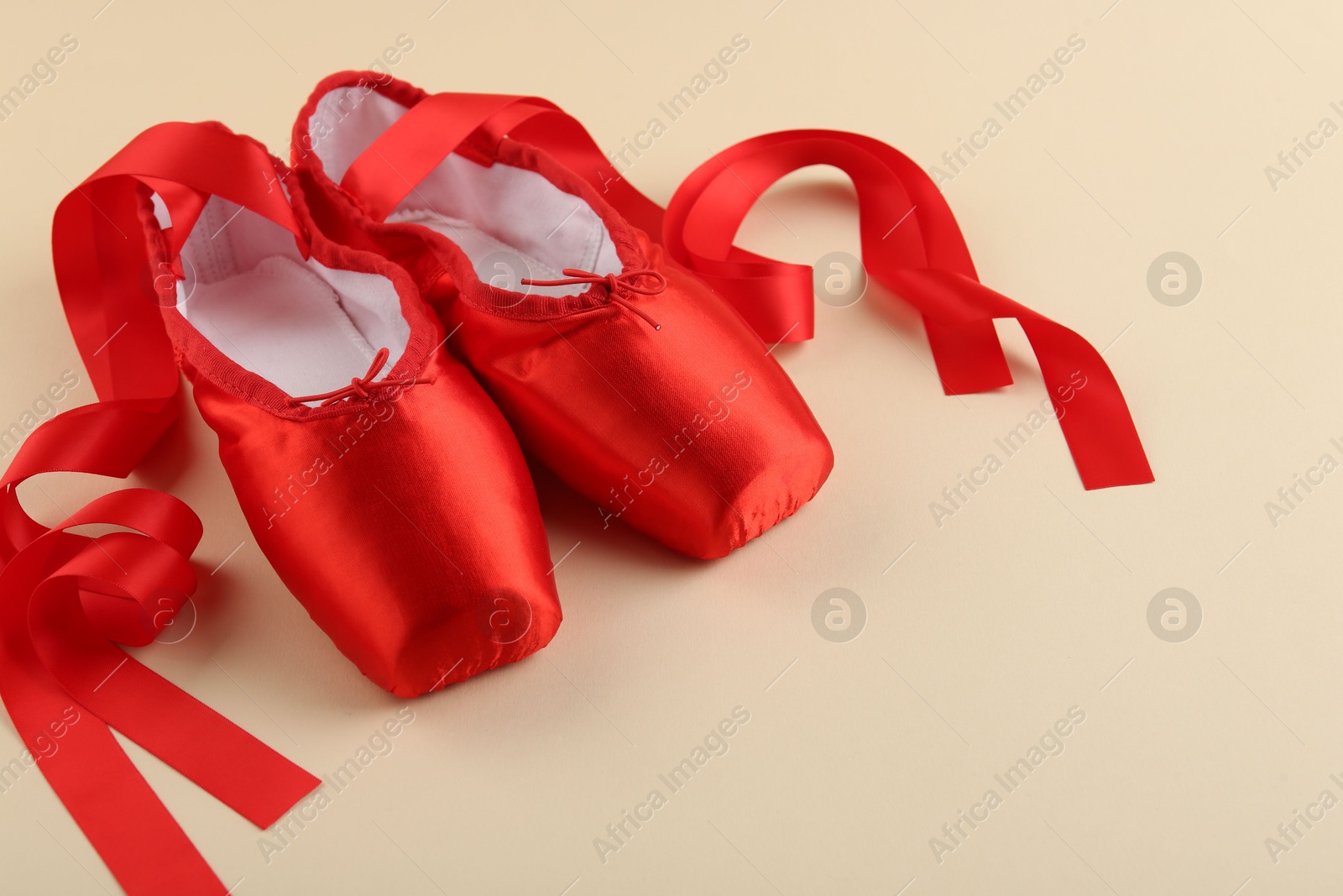 Photo of Pair of red pointe shoes on beige background. Space for text