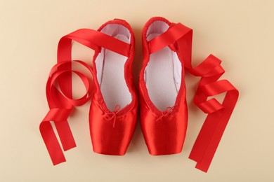 Photo of Pair of red pointe shoes on beige background