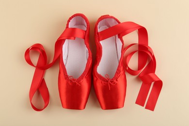 Photo of Pair of red pointe shoes on beige background