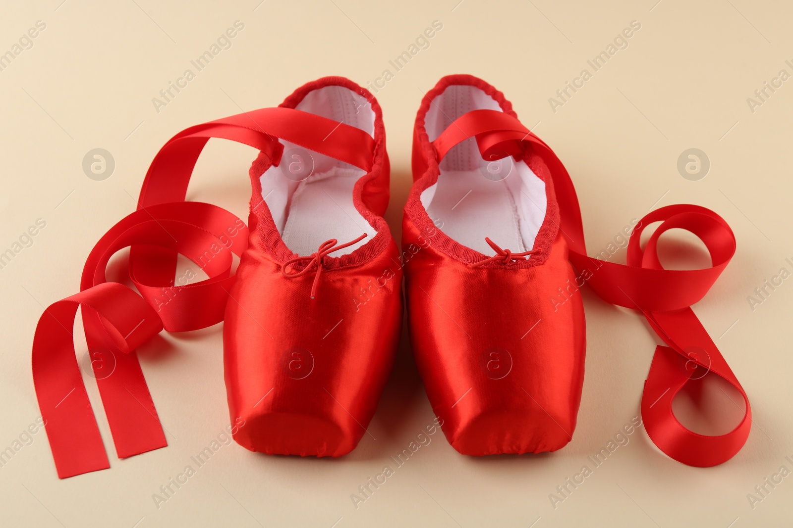 Photo of Pair of red pointe shoes on beige background, closeup