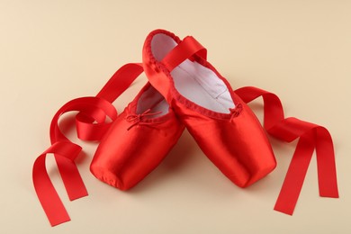 Photo of Pair of red pointe shoes on beige background