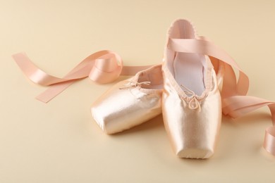 Photo of Pair of beautiful pointe shoes on beige background