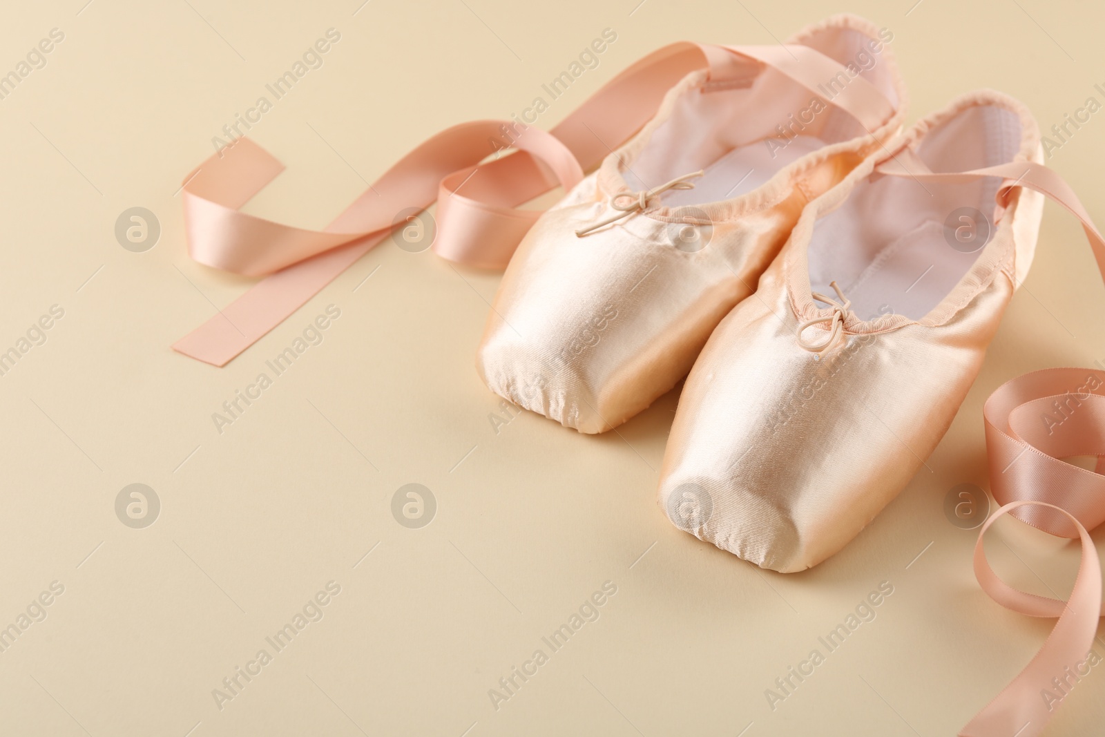 Photo of Pair of beautiful pointe shoes on beige background. Space for text