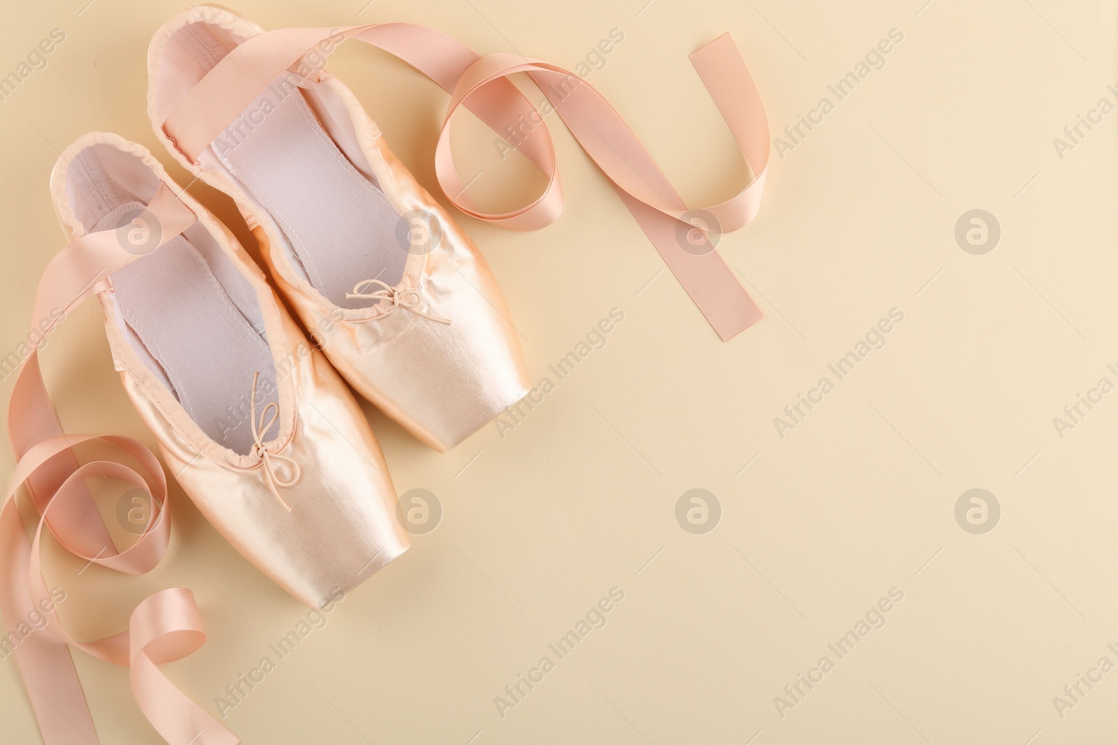 Photo of Pair of beautiful pointe shoes on beige background, top view. Space for text