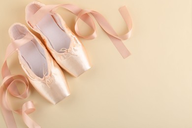 Photo of Pair of beautiful pointe shoes on beige background, top view. Space for text