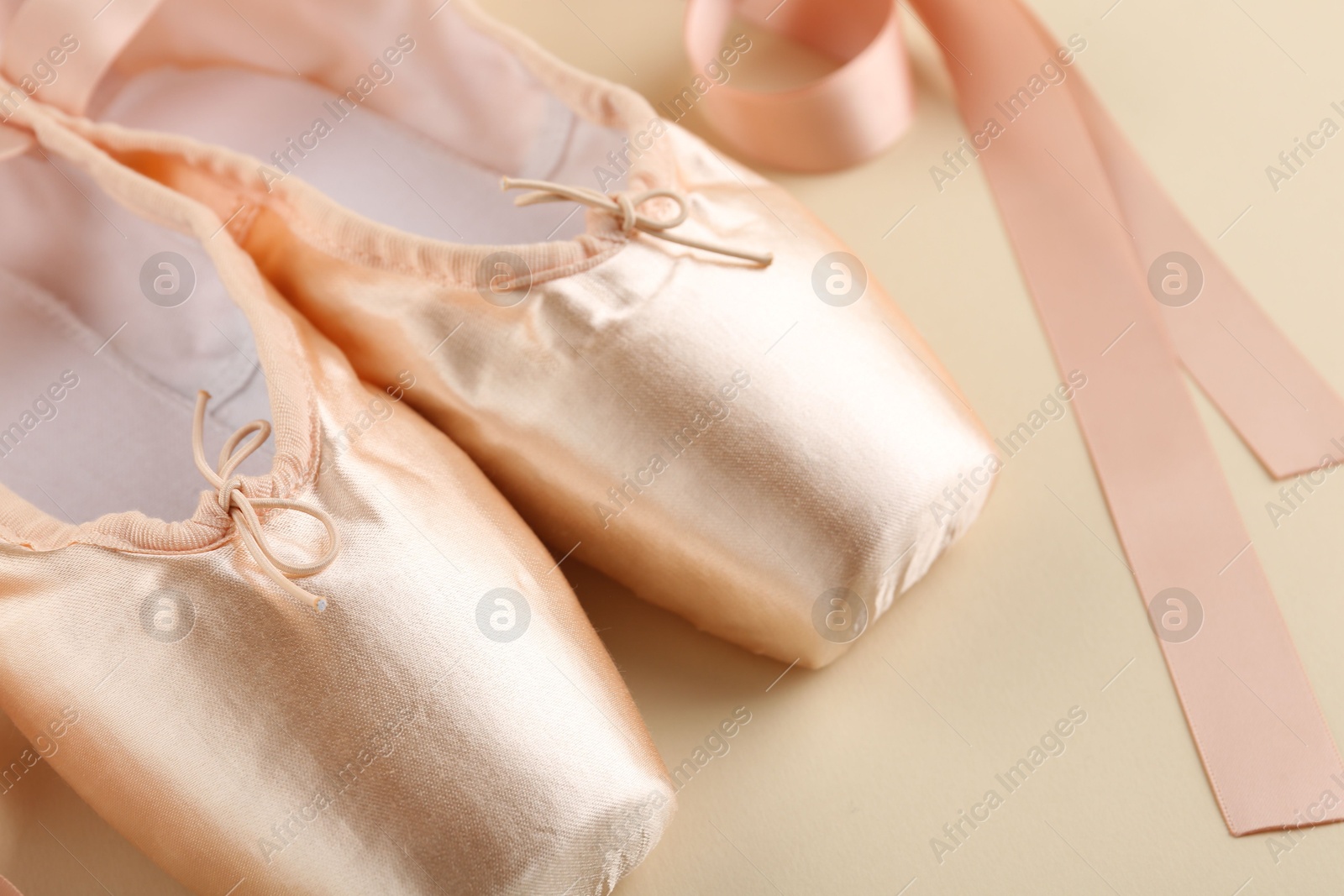 Photo of Pair of beautiful pointe shoes on beige background, closeup