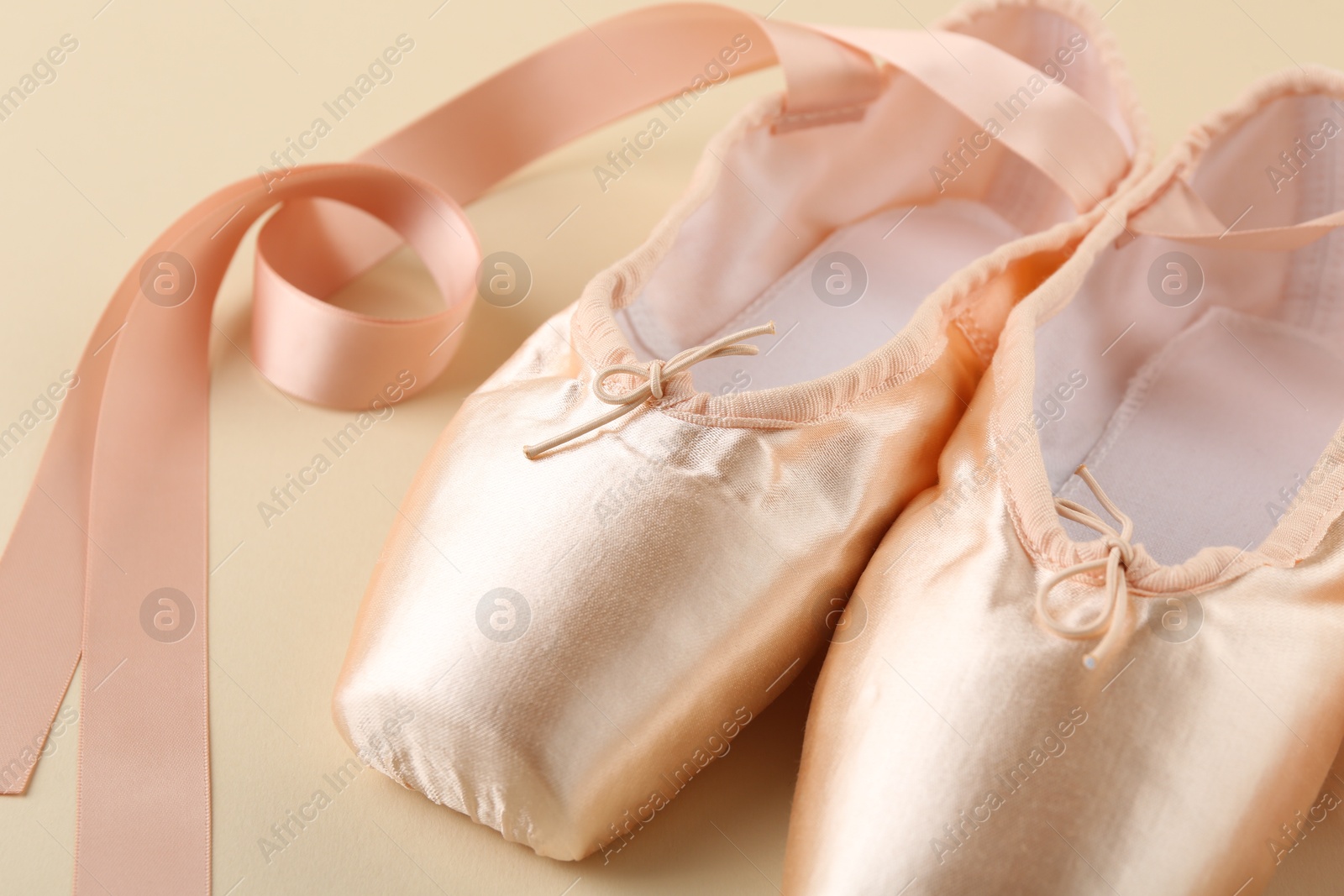 Photo of Pair of beautiful pointe shoes on beige background, closeup