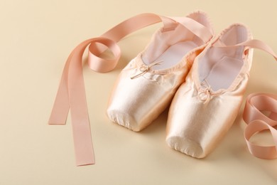 Photo of Pair of beautiful pointe shoes on beige background