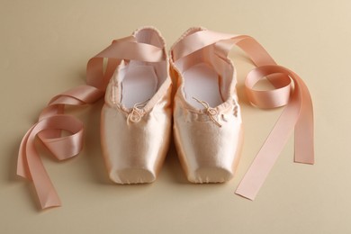 Photo of Pair of beautiful pointe shoes on beige background