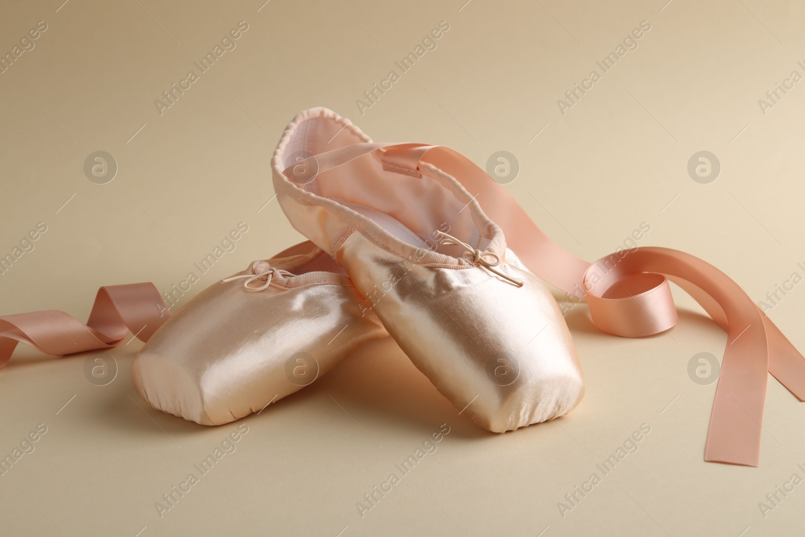 Photo of Pair of beautiful pointe shoes on beige background