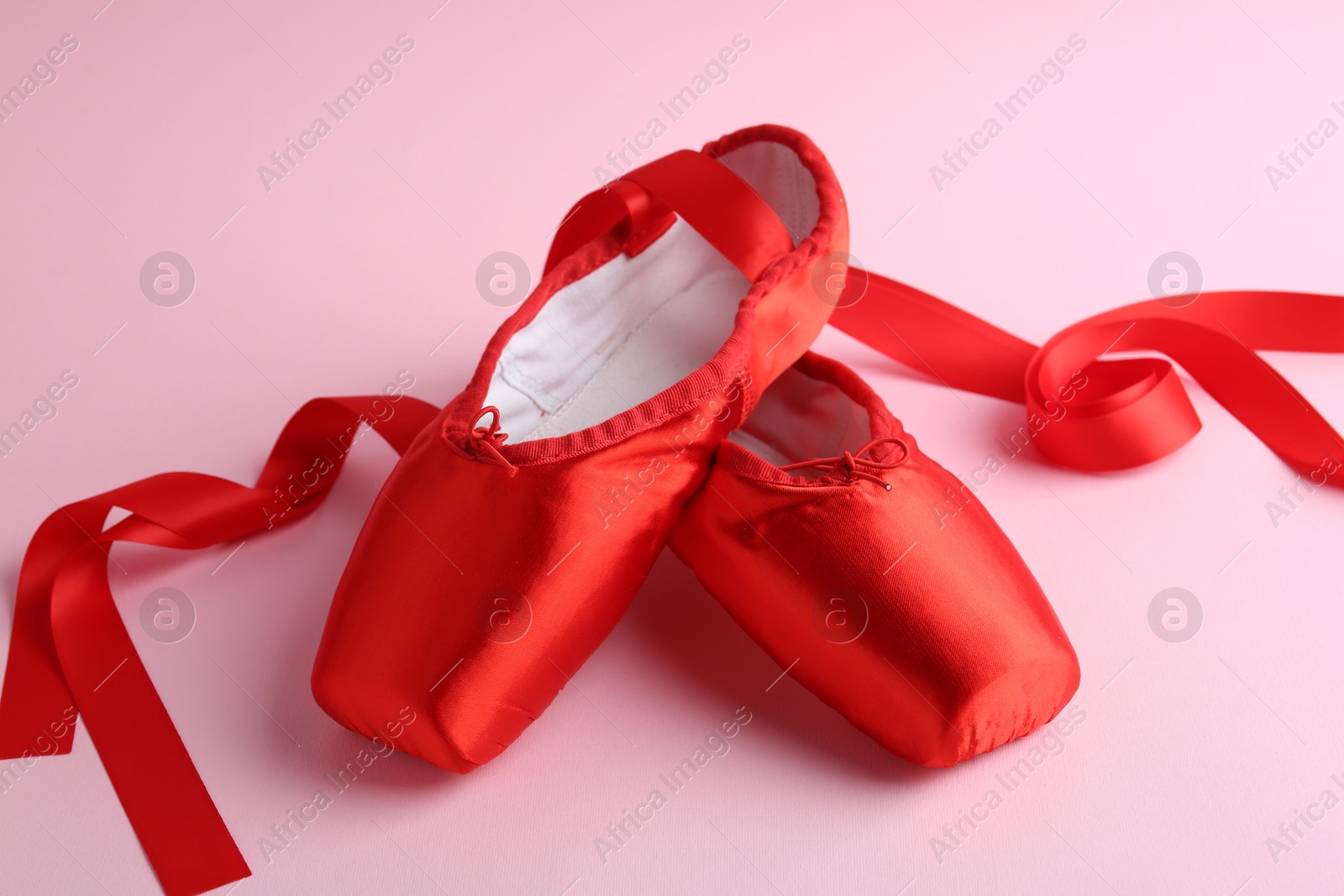 Photo of Pair of beautiful red pointe shoes on pink background, closeup