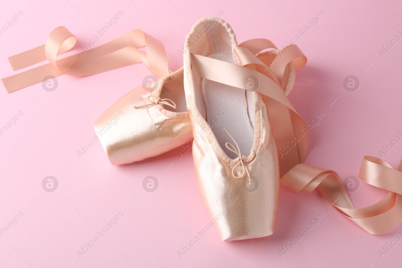 Photo of Pair of beautiful pointe shoes on pink background