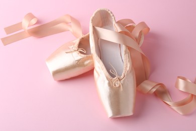 Photo of Pair of beautiful pointe shoes on pink background