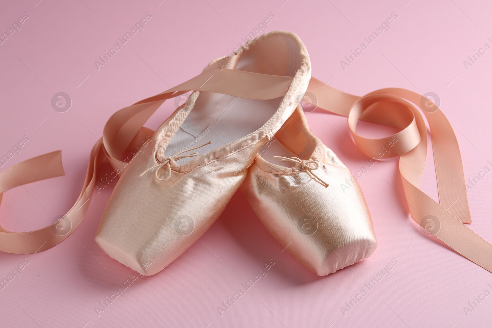 Photo of Pair of beautiful pointe shoes on pink background