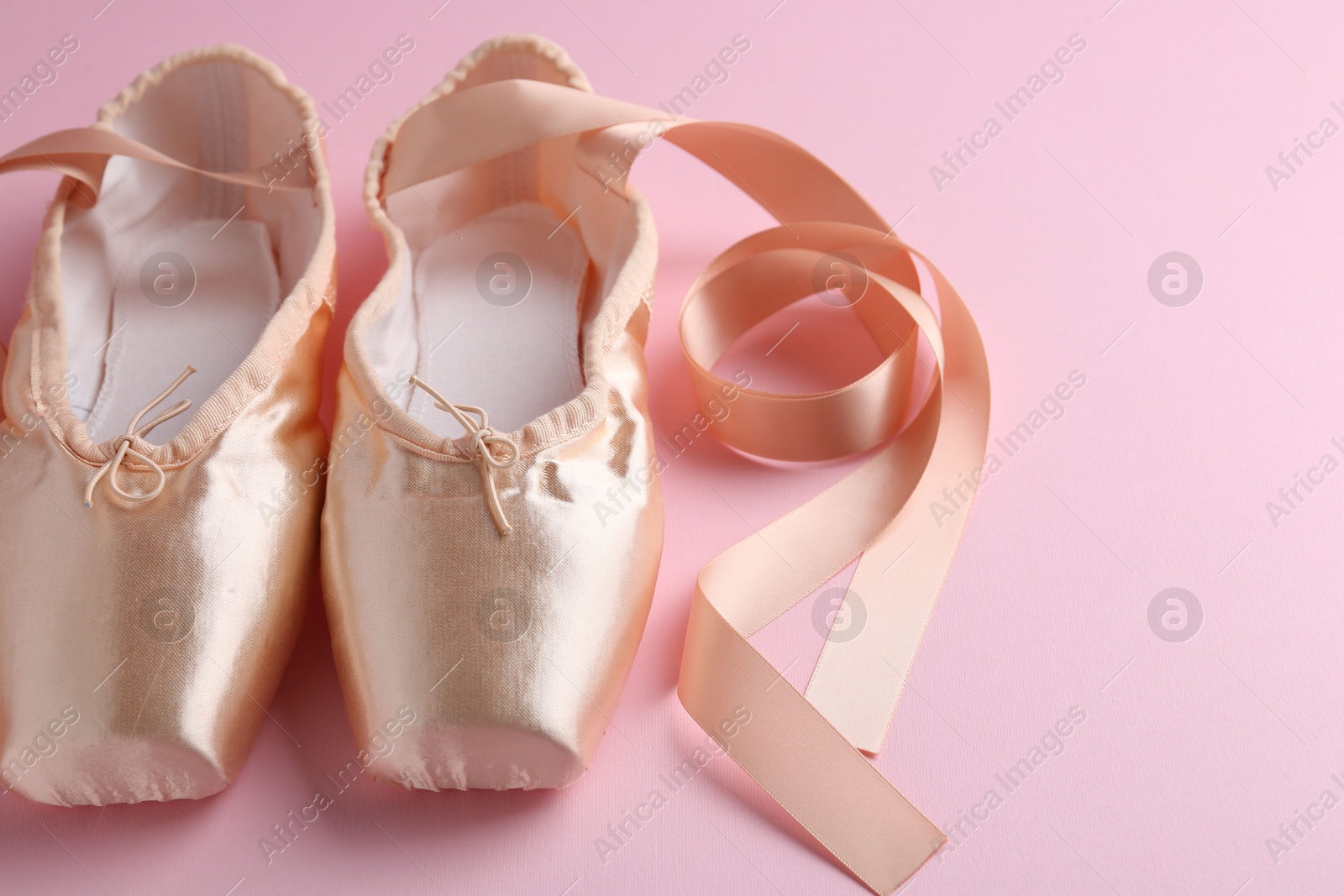 Photo of Pair of beautiful pointe shoes on pink background, closeup. Space for text