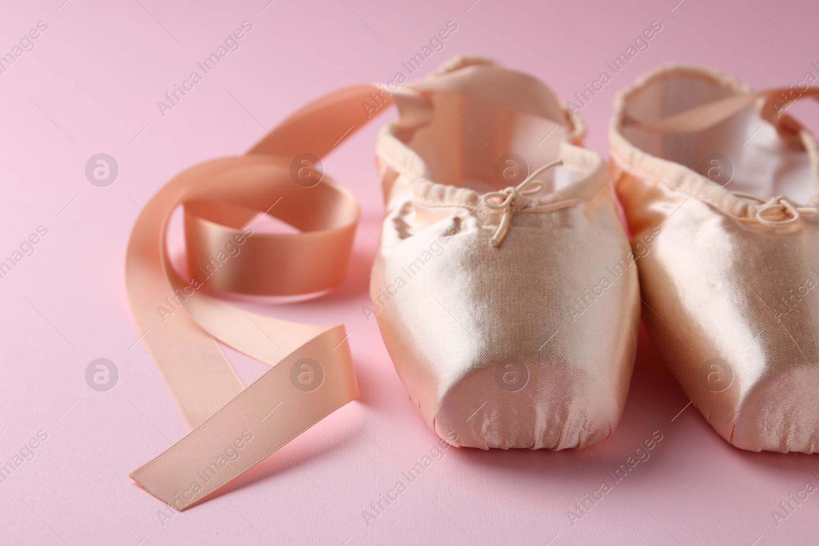 Photo of Pair of beautiful pointe shoes on pink background, closeup