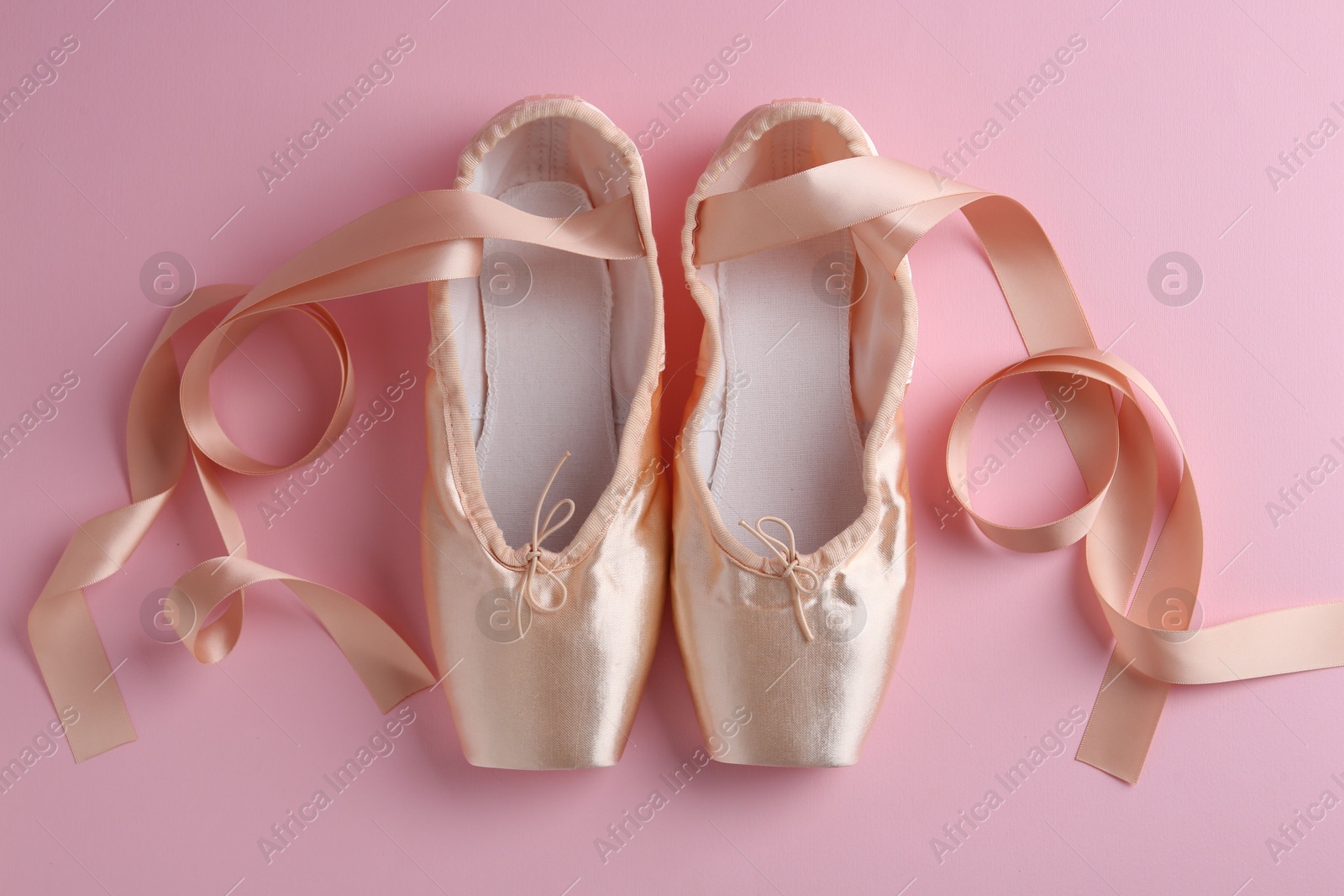 Photo of Pair of beautiful pointe shoes on pink background, top view