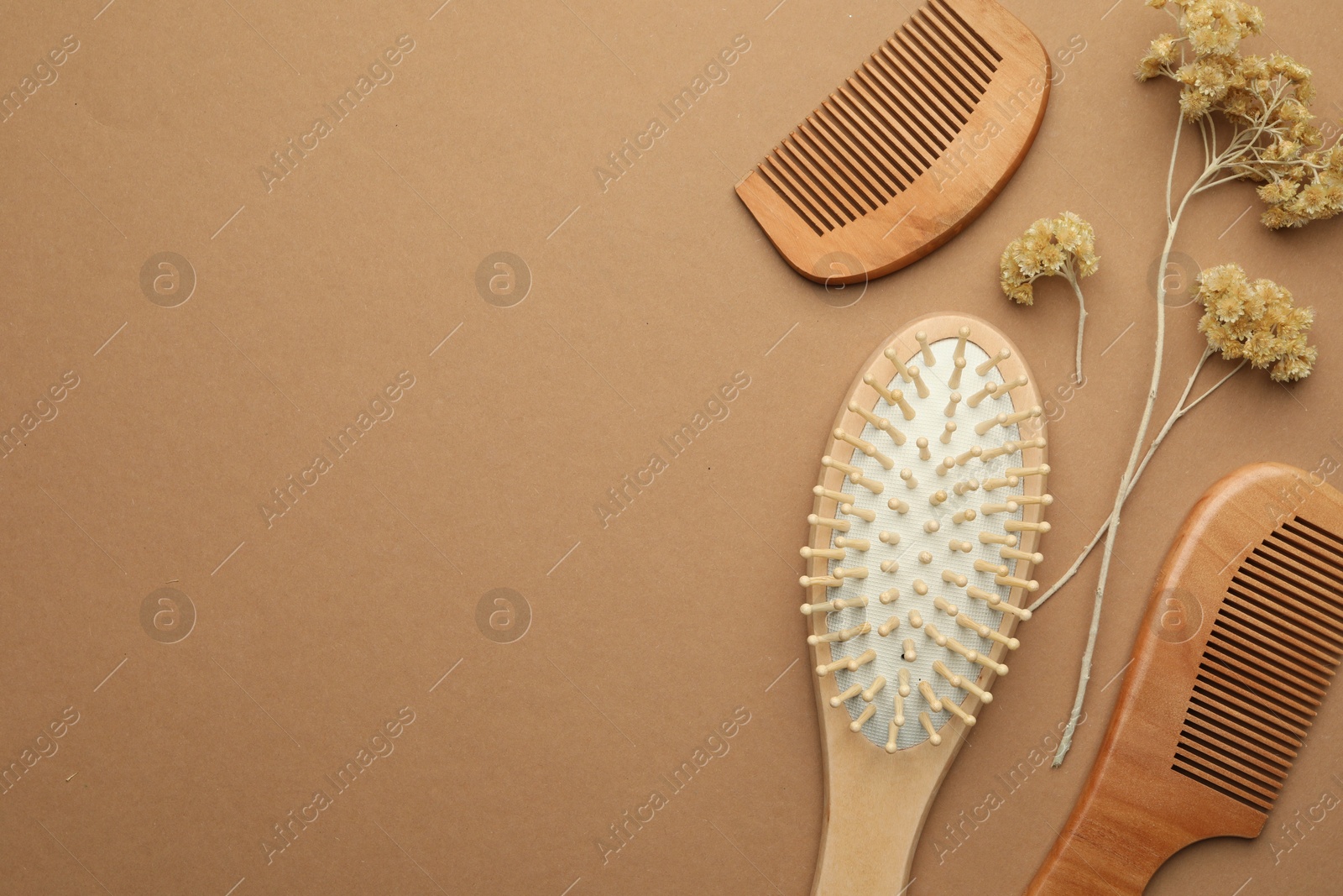 Photo of Wooden hair brush, combs and dried flowers on beige background, flat lay. Space for text